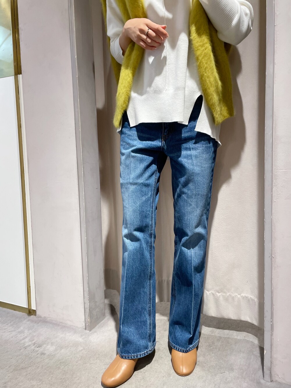 ブルー系のデニムパンツ、ホワイト系のニット/セーター、イエロー系のカーディガン/ボレロを着用したレディースの秋コーディネートの4枚目の写真