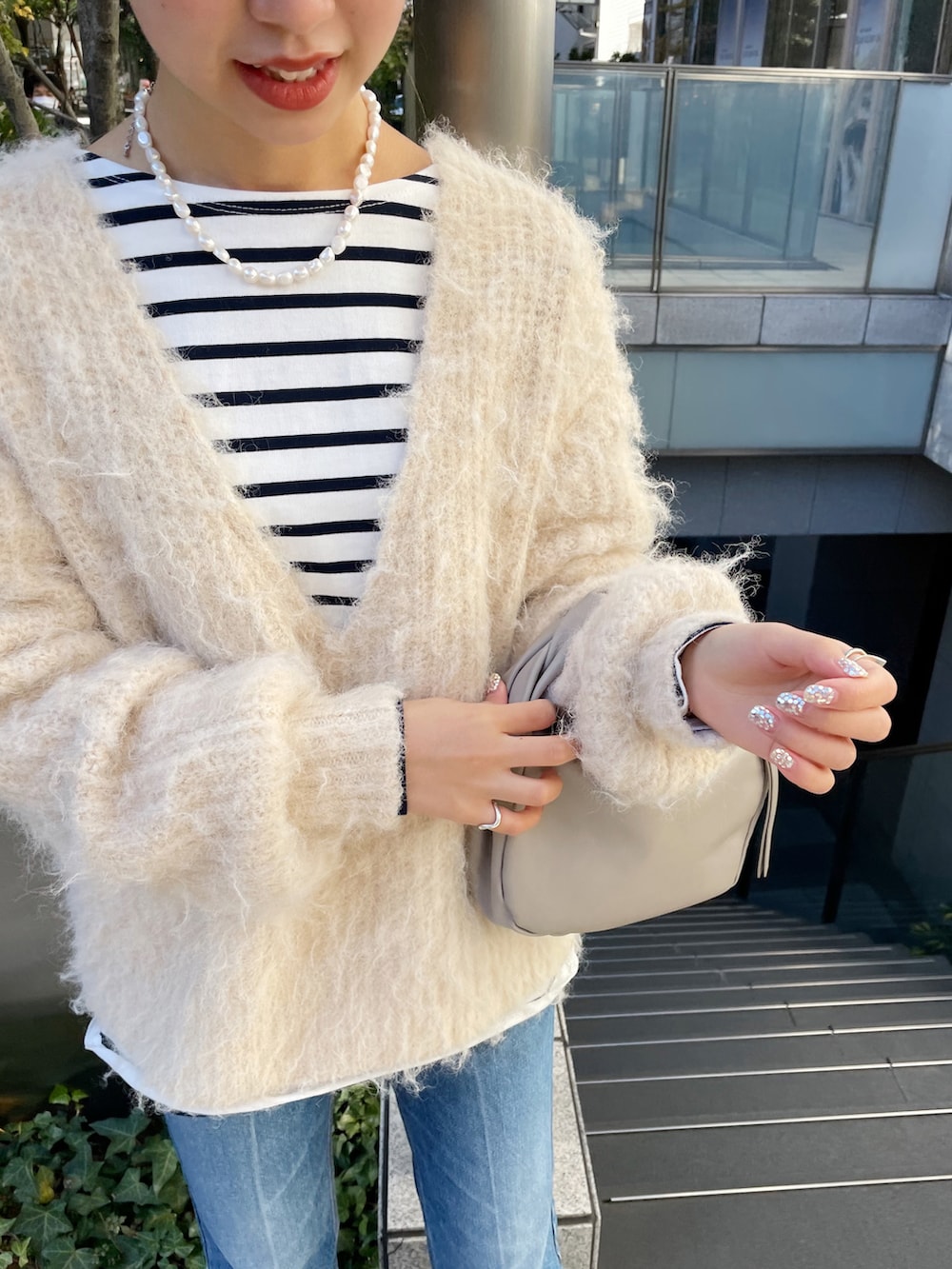 ブルー系のデニムパンツ、ベージュ系のハンドバッグ、ベージュ系のニット/セーターを着用したレディースの冬コーディネートの3枚目の写真