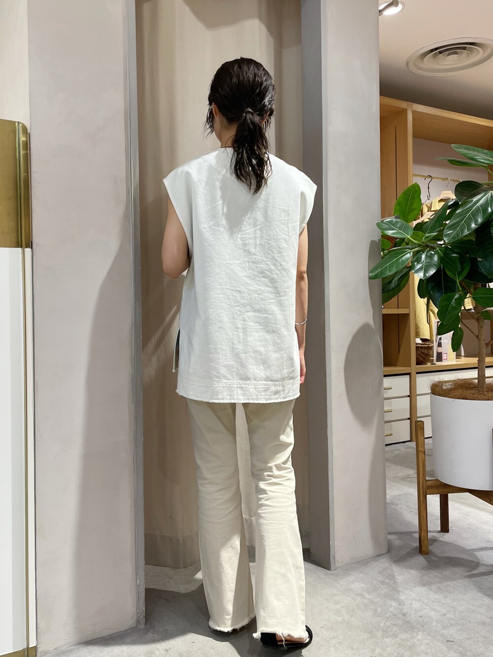 ベージュ系のデニムパンツ、ブラック系のサンダル、ホワイト系のベストを着用したレディースの夏コーディネートの5枚目の写真