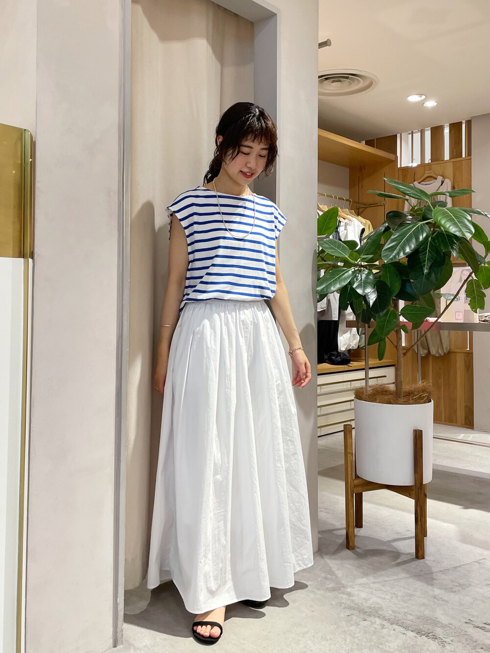 ホワイト系のスカート、ブラック系のサンダル、ブルー系のTシャツ/カットソーを着用したレディースの夏コーディネートの2枚目の写真