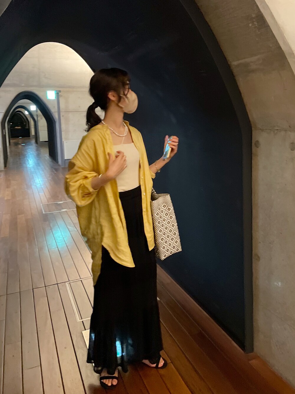 イエロー系のシャツ/ブラウス、ブラック系のスカート、ブラック系のサンダルを着用したレディースの夏コーディネートの2枚目の写真