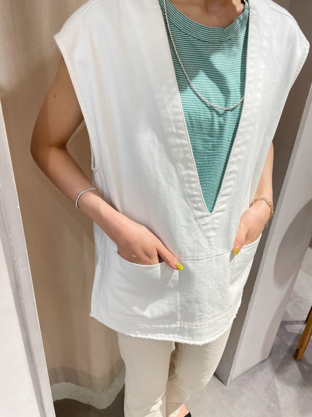 ベージュ系のデニムパンツ、ブラック系のサンダル、ホワイト系のベストを着用したレディースの夏コーディネートの4枚目の写真