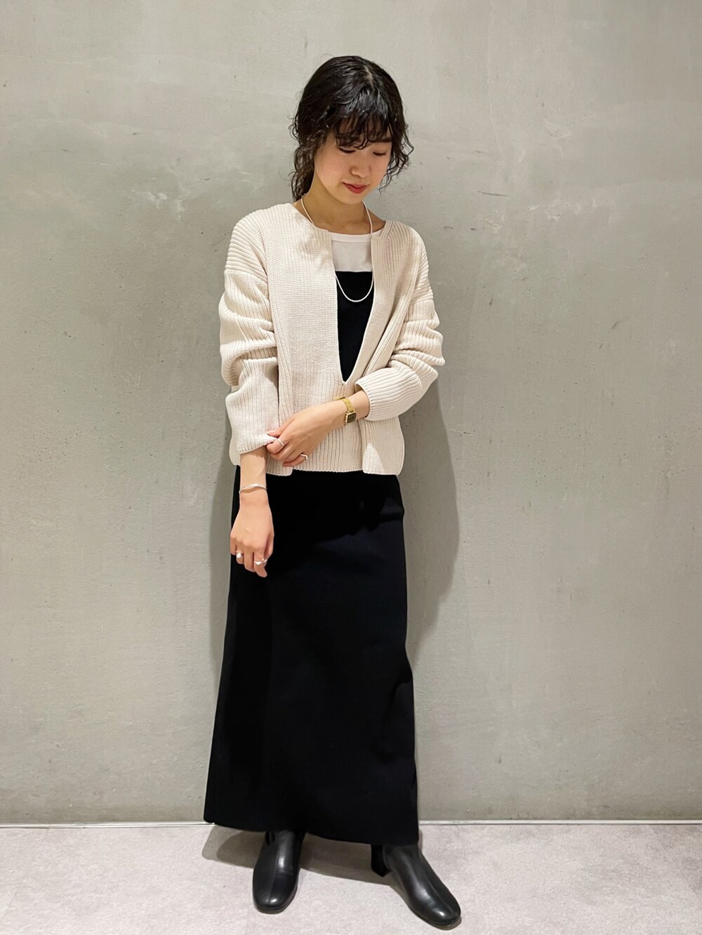 ホワイト系のニット/セーター、ブラック系のワンピース、ブラック系のブーツを着用したレディースの秋コーディネートの2枚目の写真