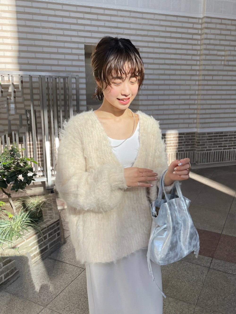 シルバー系のショルダーバッグ、グレー系のスカート、ブラウン系のブーツを着用したレディースの冬コーディネートの2枚目の写真