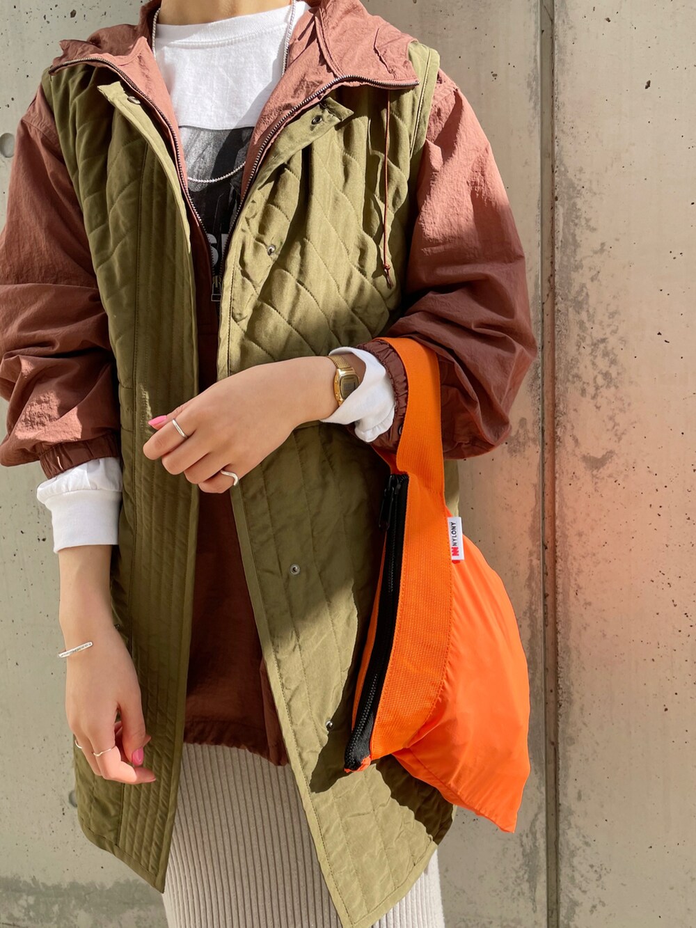 グレー系のスカート、グリーン系のベスト、ブラウン系のブルゾンを着用したレディースの冬コーディネートの2枚目の写真