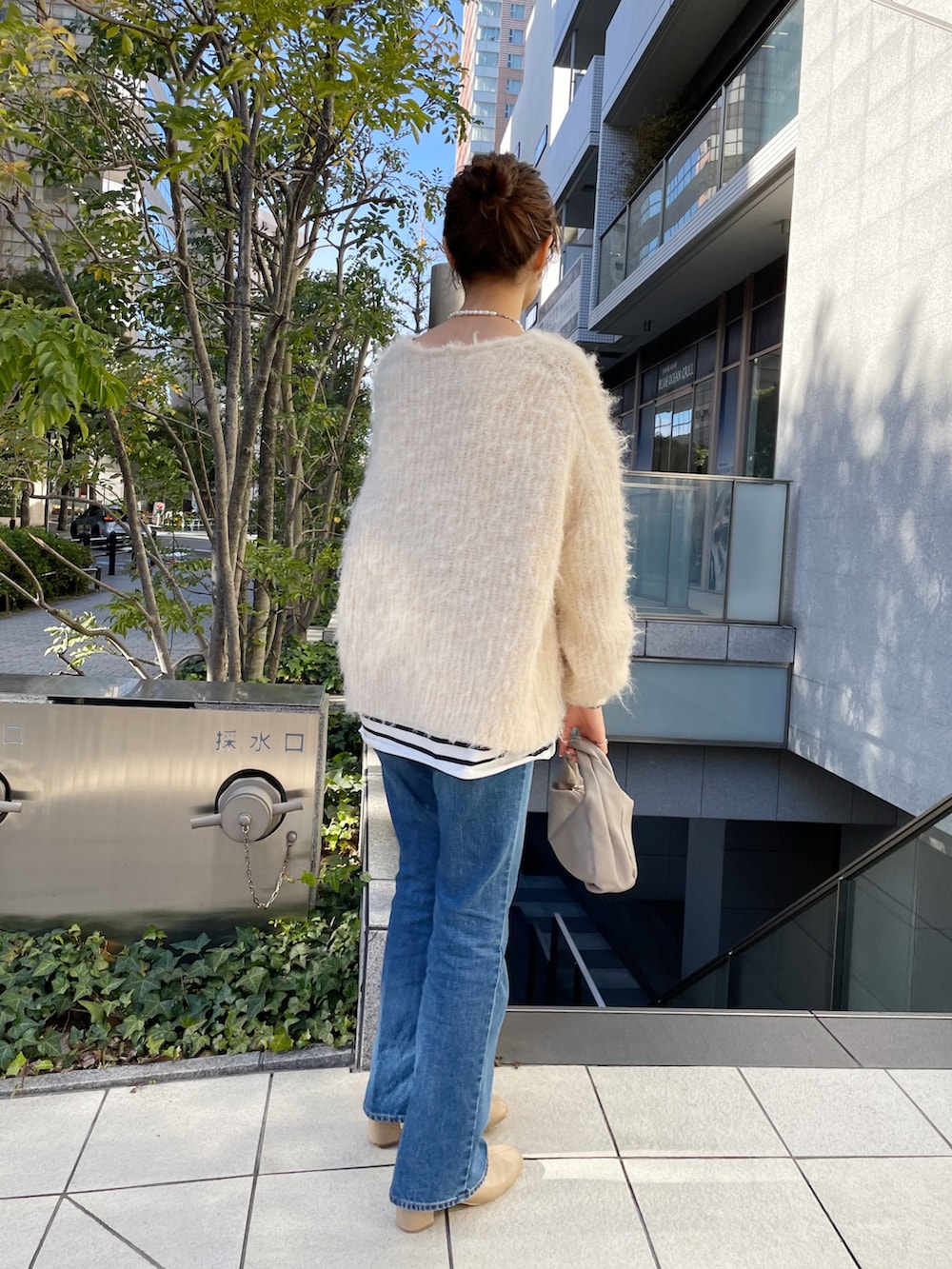 ブルー系のデニムパンツ、ベージュ系のハンドバッグ、ベージュ系のニット/セーターを着用したレディースの冬コーディネートの5枚目の写真