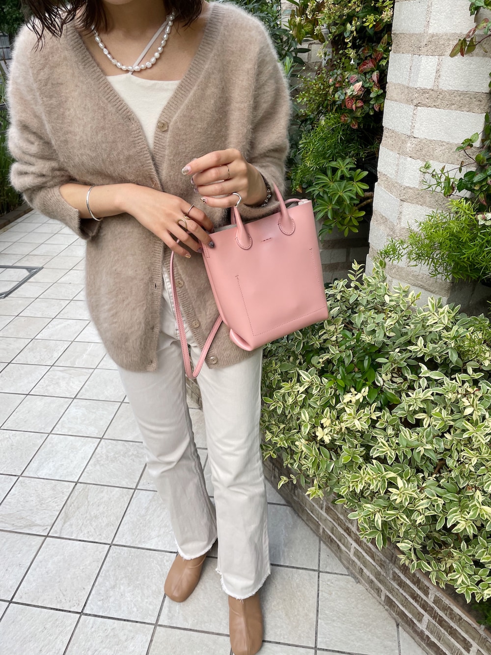 ピンク系のトートバッグ、ベージュ系のカーディガン/ボレロ、ホワイト系のキャミソールを着用したレディースの秋コーディネートの4枚目の写真