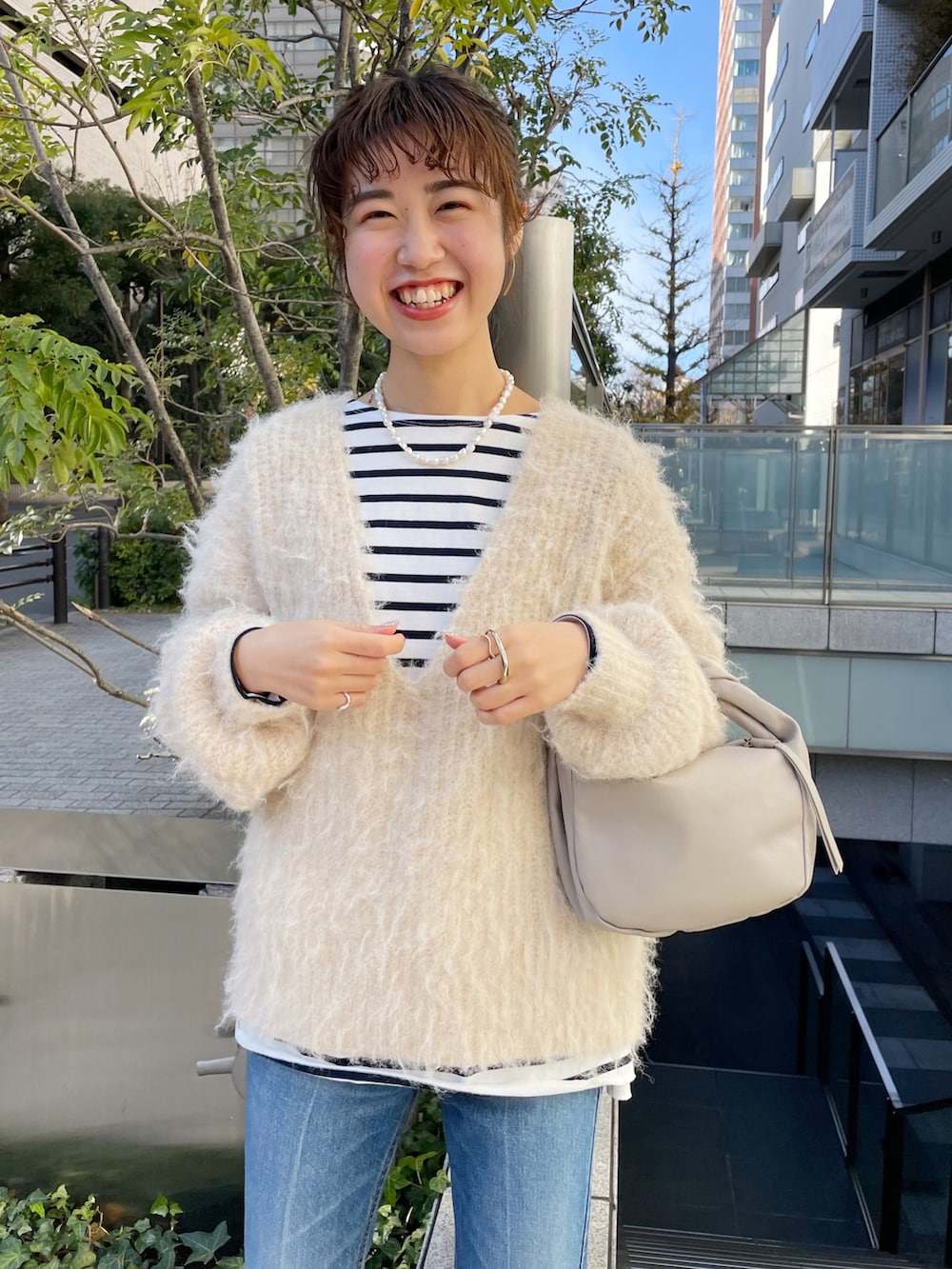 ブルー系のデニムパンツ、ベージュ系のハンドバッグ、ベージュ系のニット/セーターを着用したレディースの冬コーディネートの2枚目の写真