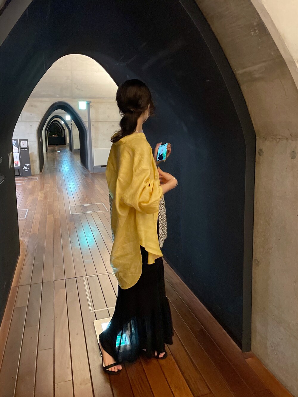 イエロー系のシャツ/ブラウス、ブラック系のスカート、ブラック系のサンダルを着用したレディースの夏コーディネートの3枚目の写真