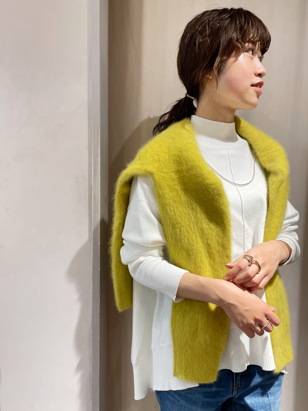 ブルー系のデニムパンツ、ホワイト系のニット/セーター、イエロー系のカーディガン/ボレロを着用したレディースの秋コーディネートの3枚目の写真