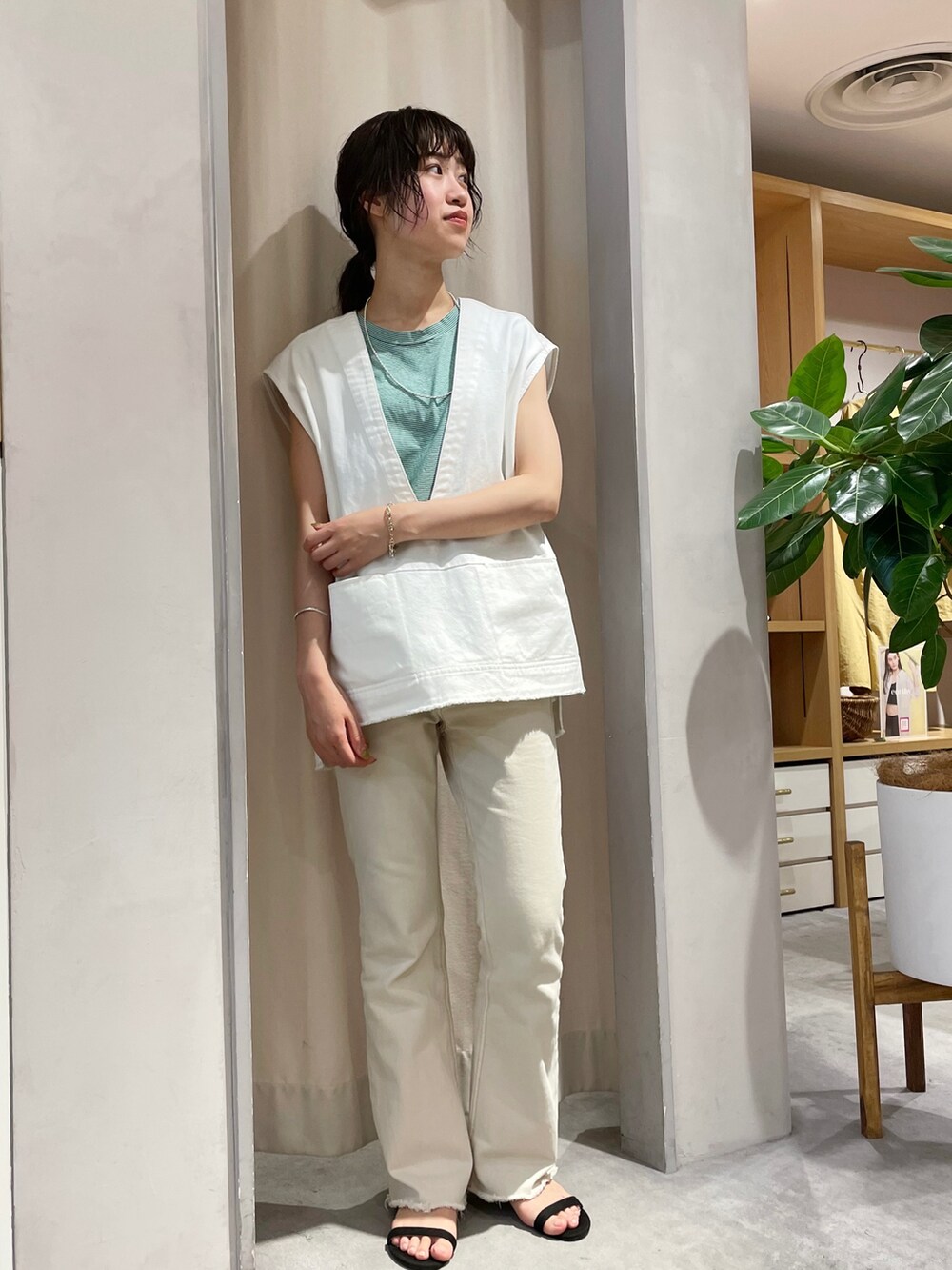 ベージュ系のデニムパンツ、ブラック系のサンダル、ホワイト系のベストを着用したレディースの夏コーディネートの2枚目の写真