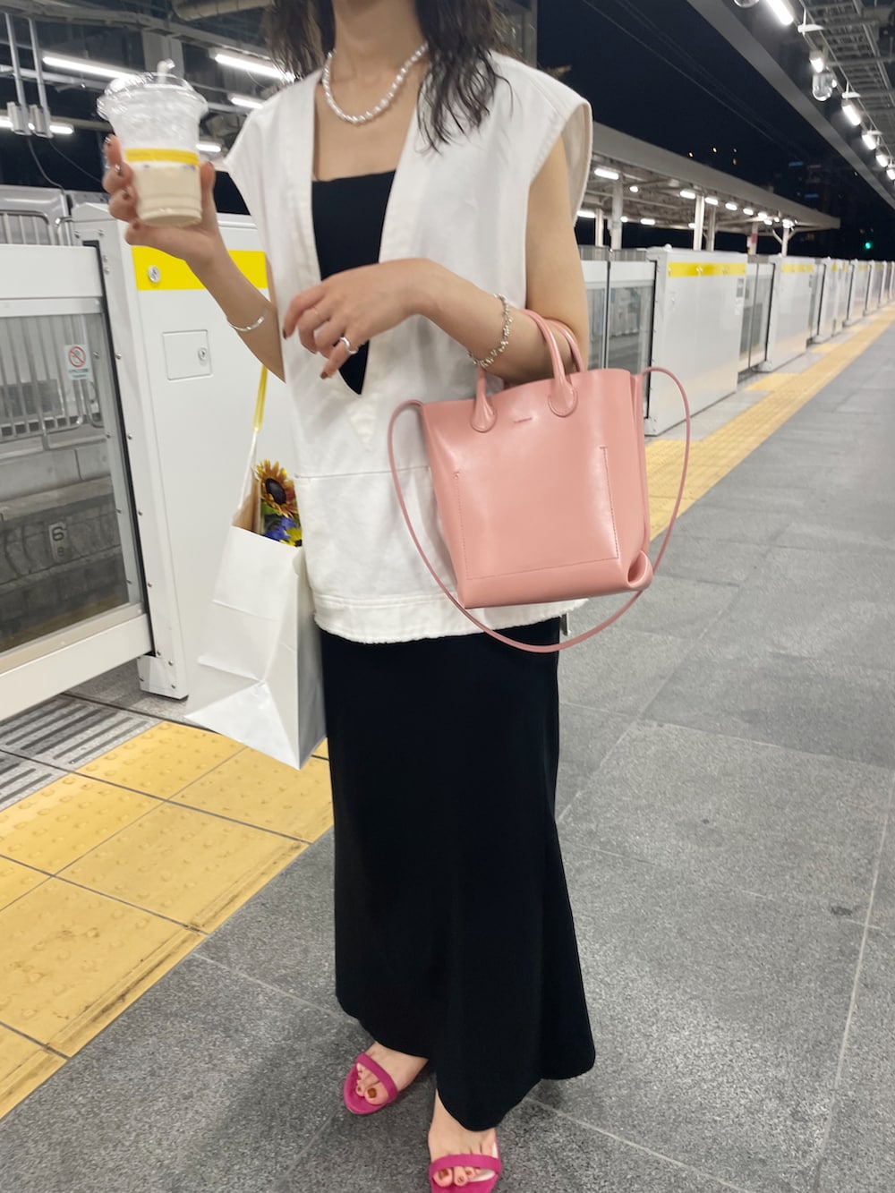 ピンク系のサンダル、ブラック系のワンピース、ホワイト系のベストを着用したレディースの夏コーディネートの4枚目の写真