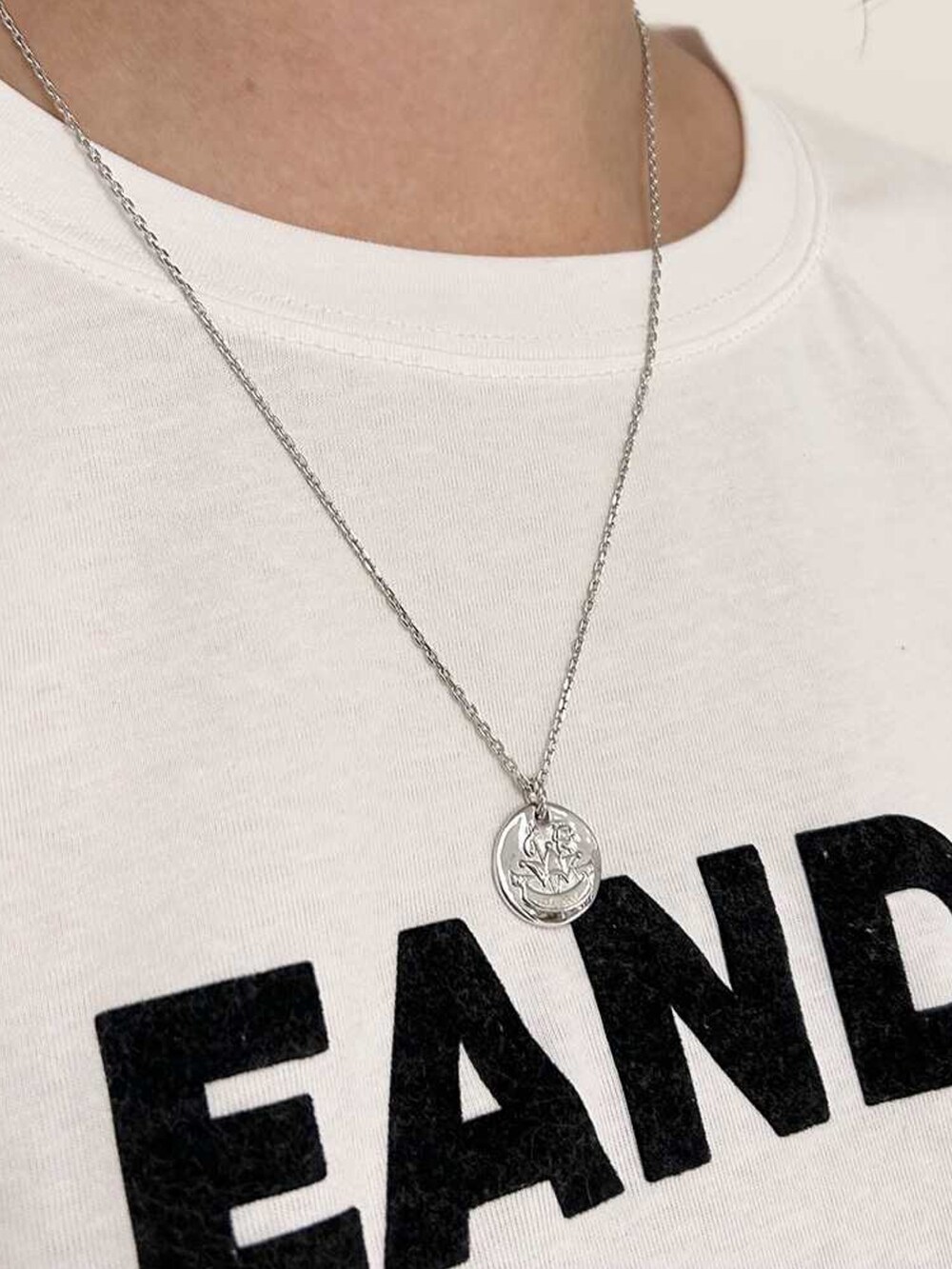 ホワイト系のTシャツ/カットソー、ブラック系のサンダル、シルバー系のネックレスを着用したレディースの夏コーディネートの2枚目の写真