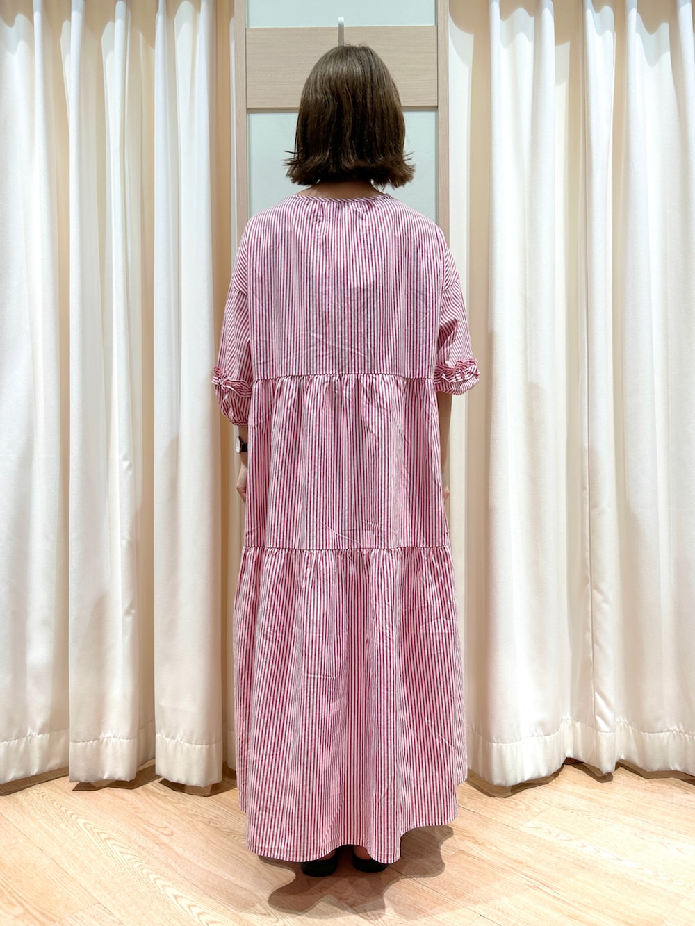 レッド系のワンピース、ホワイト系のハンドバッグ、ブラウン系のサンダルを着用したレディースの春コーディネートの2枚目の写真