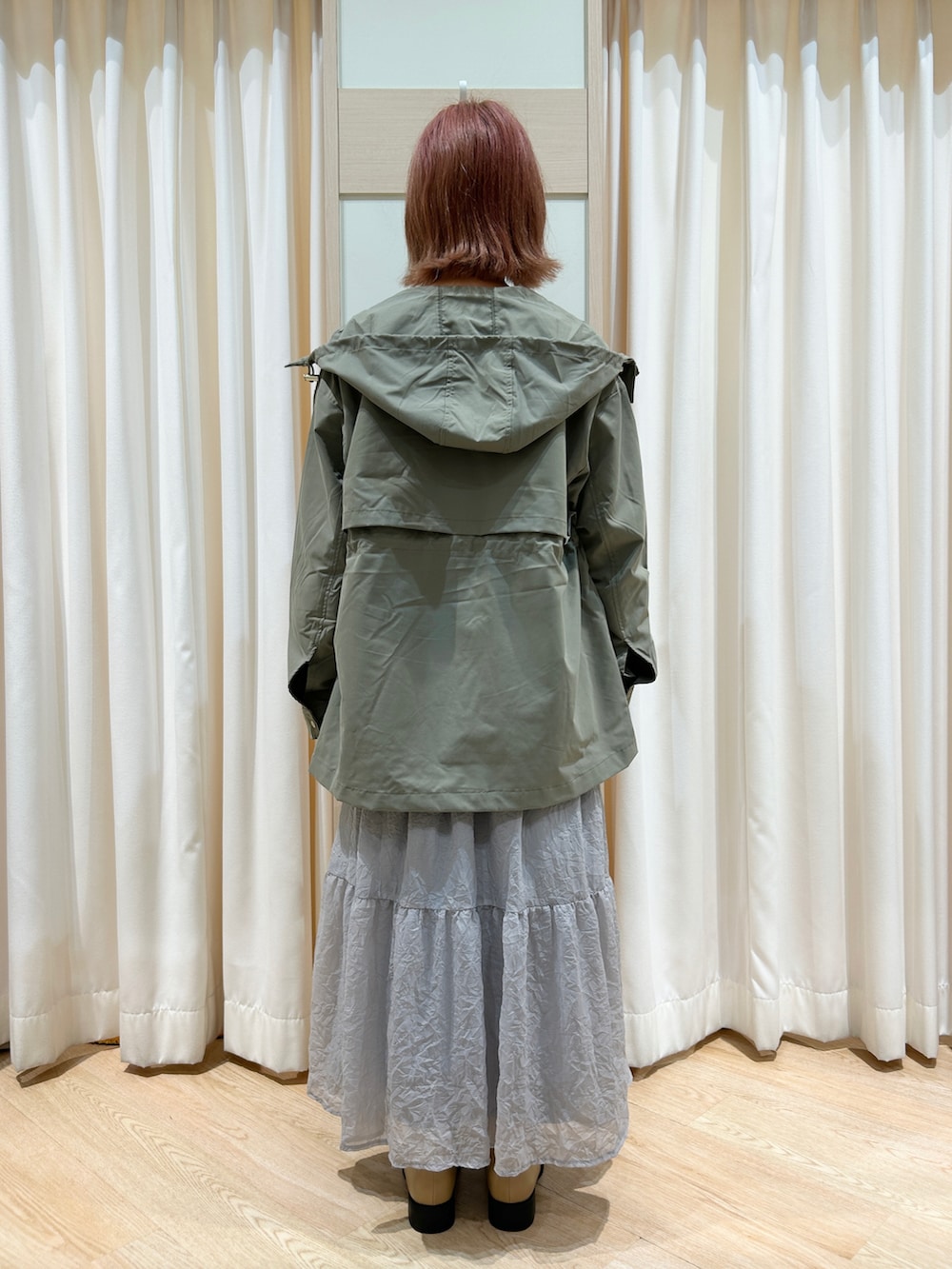 グリーン系のブルゾン、グレー系のスカート、ベージュ系のブーツを着用したレディースの秋コーディネートの2枚目の写真