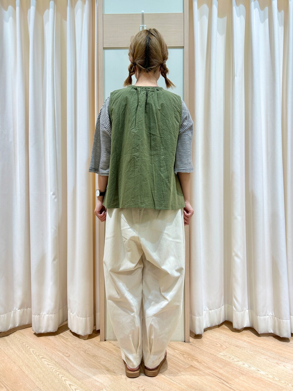 グリーン系のベスト、ホワイト系のTシャツ/カットソー、ホワイト系のパンツを着用したレディースの夏コーディネートの2枚目の写真