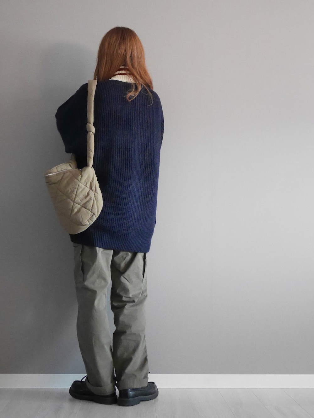 ブルー系のニット/セーター、グリーン系のパンツ、ブラウン系のメッセンジャーバッグを着用したレディースの秋コーディネートの3枚目の写真