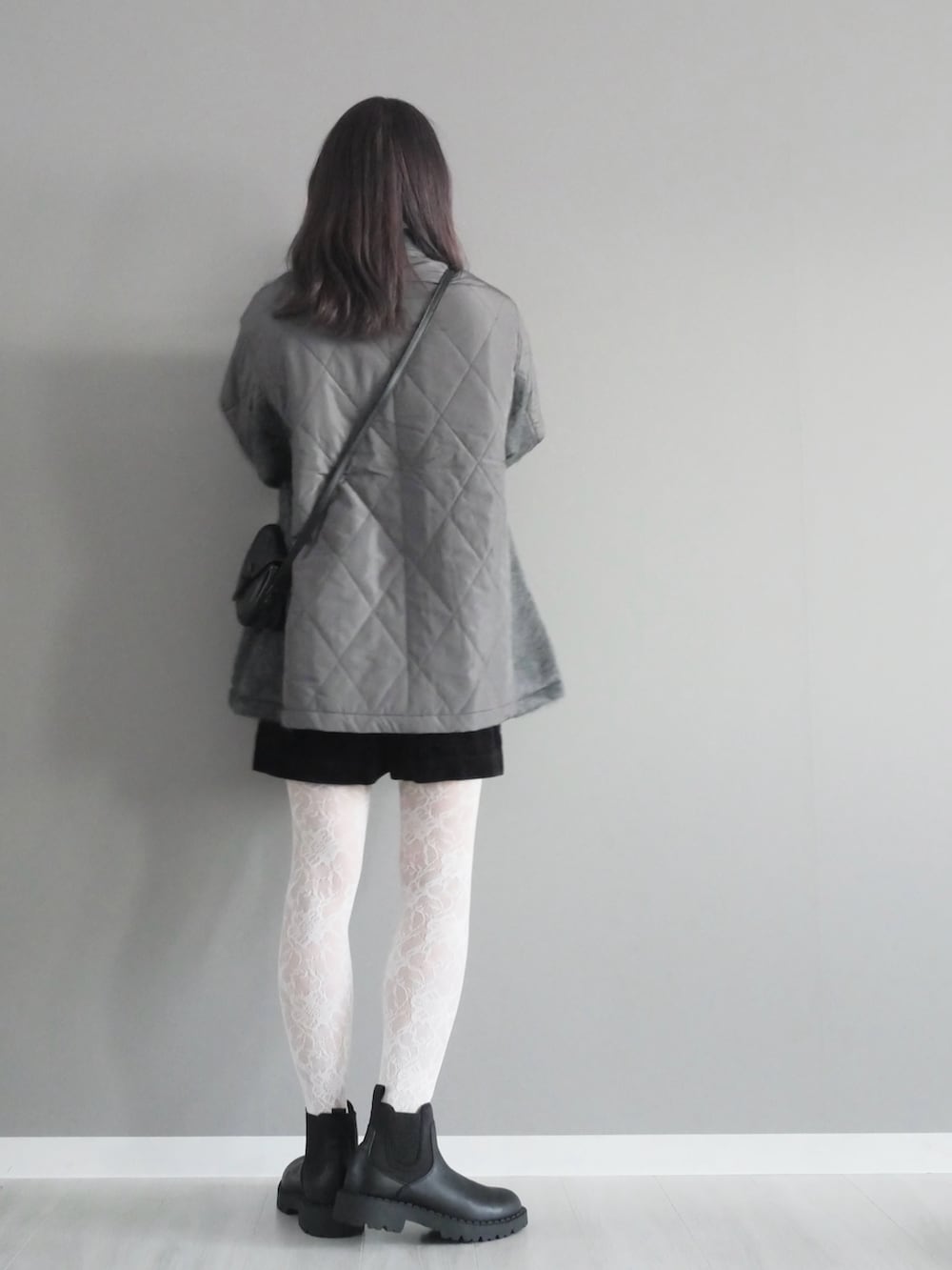 グレー系のステンカラーコート、ブラック系のパンツ、ブラック系のブーツを着用したレディースの秋コーディネートの5枚目の写真