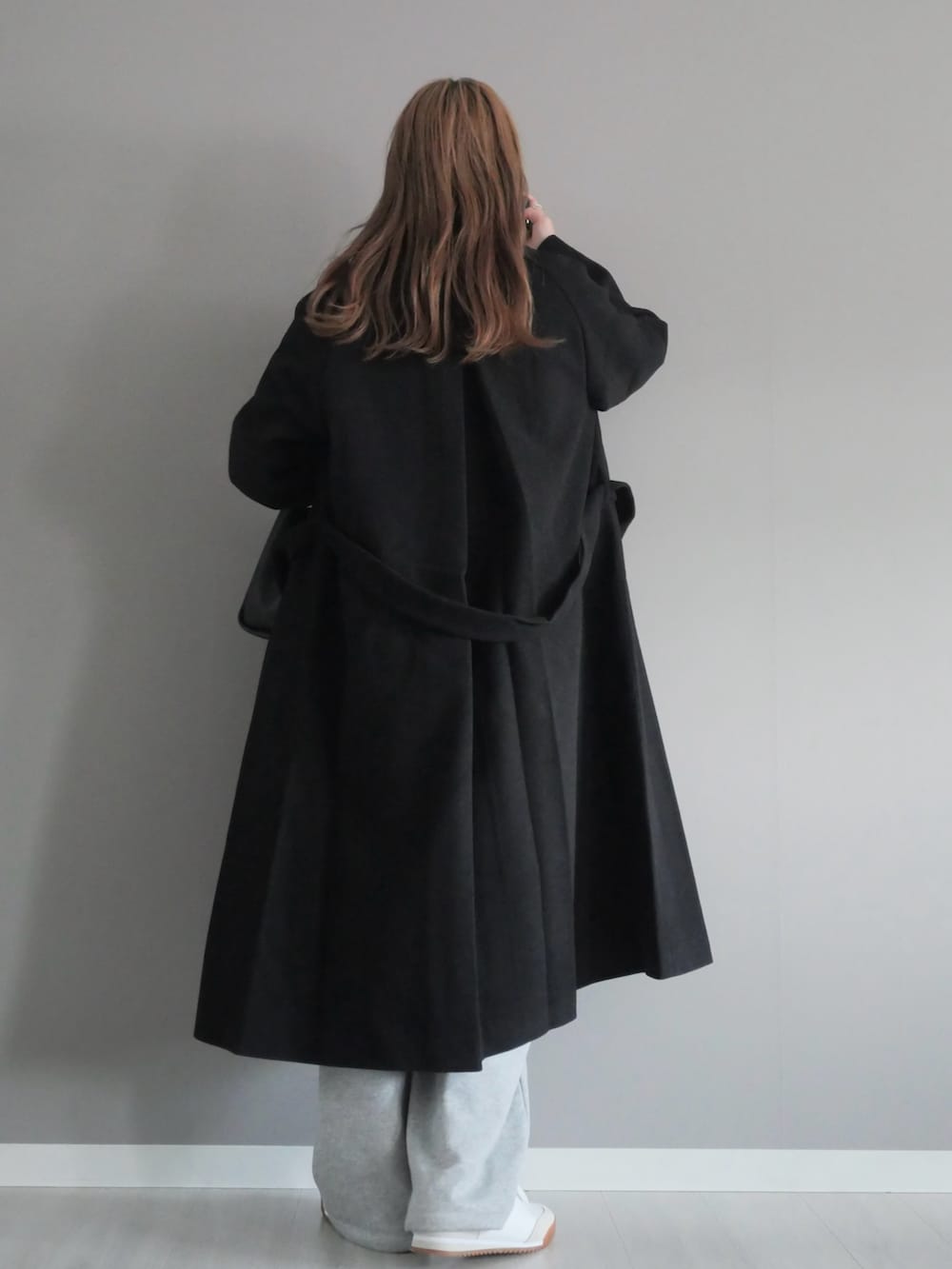 ブラック系のステンカラーコート、グレー系のスウェットパンツ、ブラック系のハンドバッグを着用したレディースの秋コーディネートの4枚目の写真