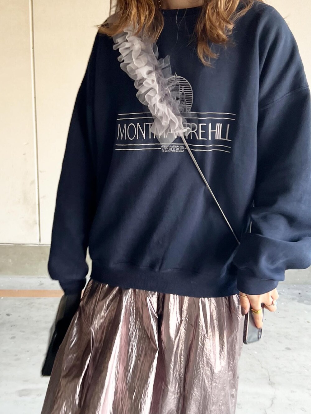 シルバー系のスカート、ブルー系のスウェット、ブラック系のブーツを着用したレディースの冬コーディネートの3枚目の写真