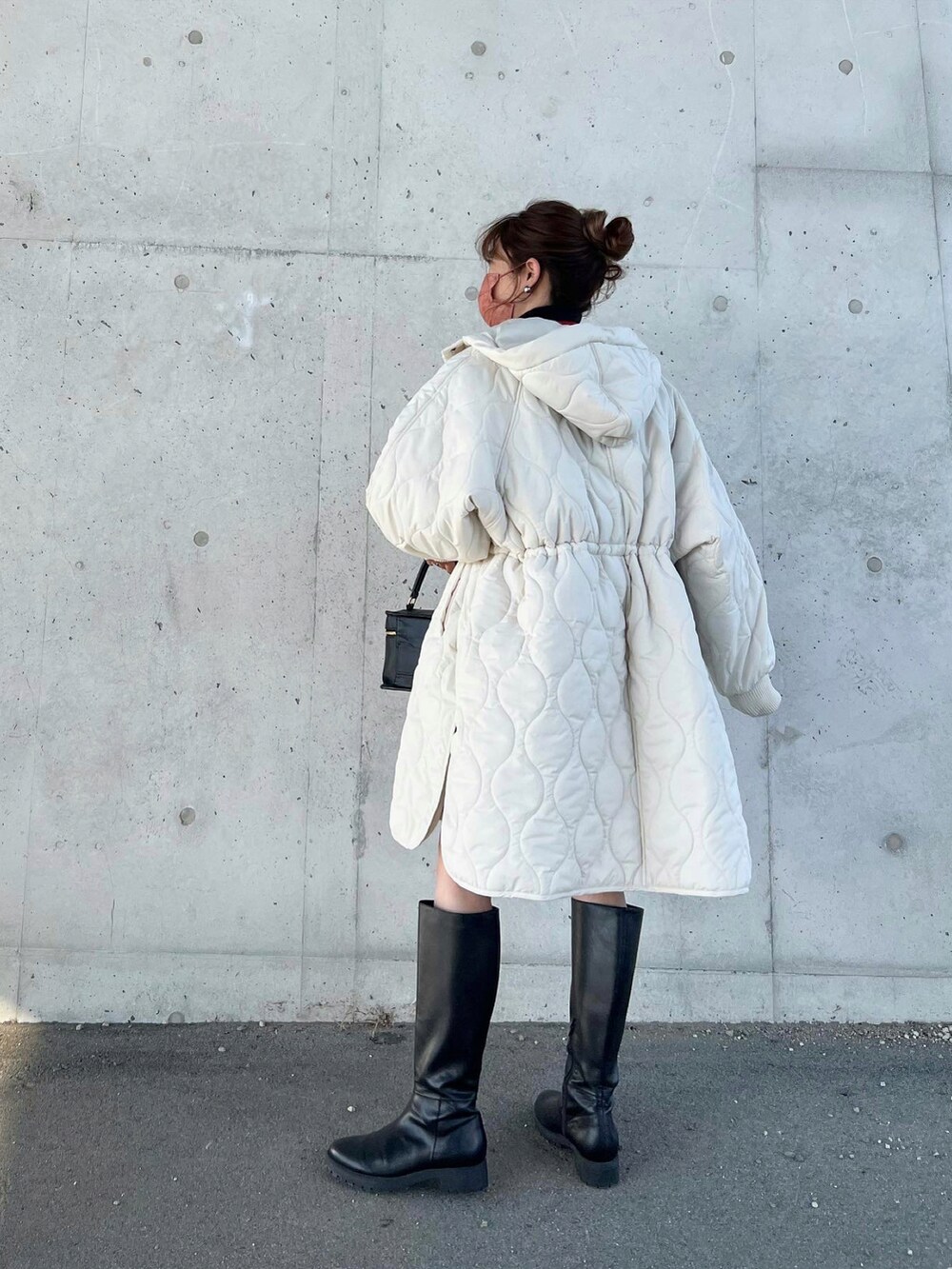 ホワイト系のダウンジャケット/コート、ブラック系のショルダーバッグ、ブラック系のブーツを着用したレディースの秋コーディネートの3枚目の写真