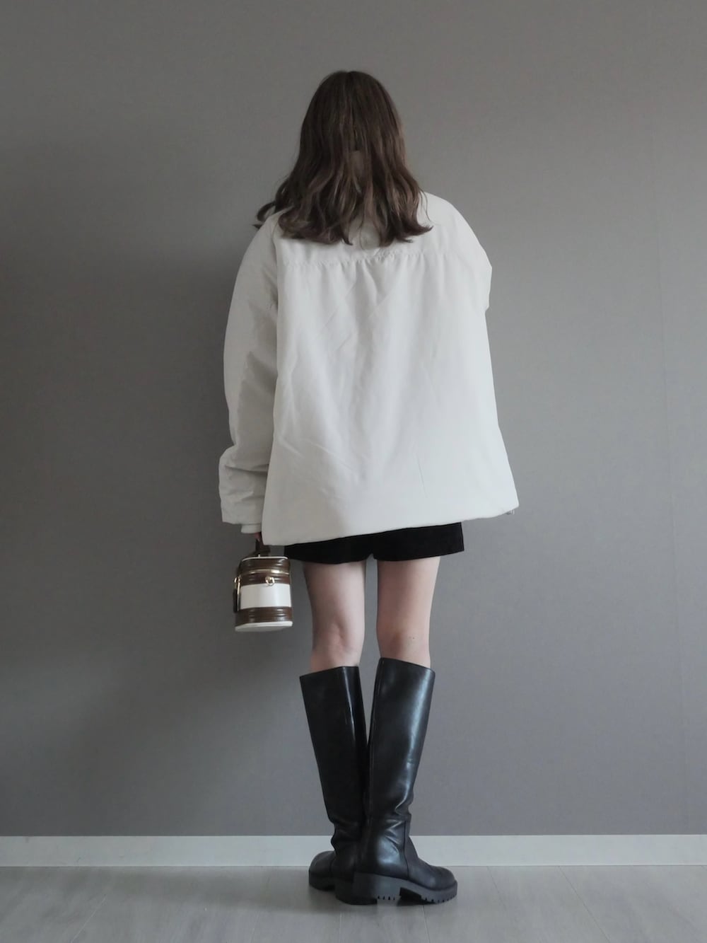 ホワイト系のブルゾン、ブラック系のパンツ、ホワイト系のハンドバッグを着用したレディースの冬コーディネートの3枚目の写真