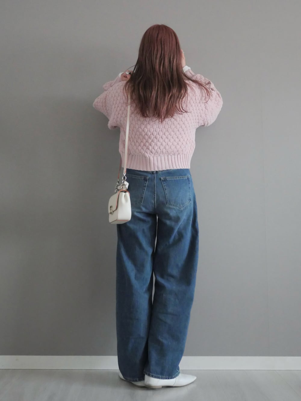 ピンク系のニット/セーター、ホワイト系のパンプス、ホワイト系のハンドバッグを着用したレディースの冬コーディネートの4枚目の写真