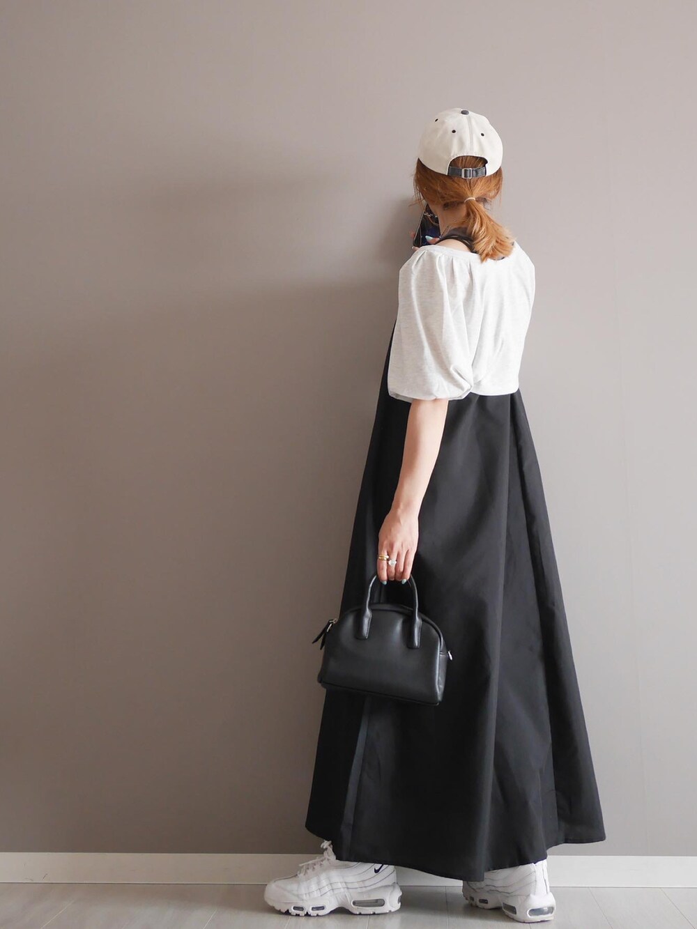 グレー系のタンクトップ、ブラック系のボストンバッグ、ホワイト系のスニーカーを着用したレディースの春コーディネートの2枚目の写真