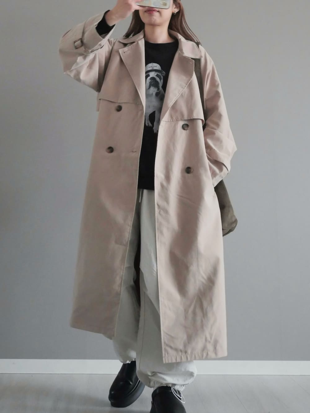 ベージュ系のトレンチコート、グリーン系のショルダーバッグ、ブラック系のスリッポンを着用したレディースの春コーディネートの2枚目の写真