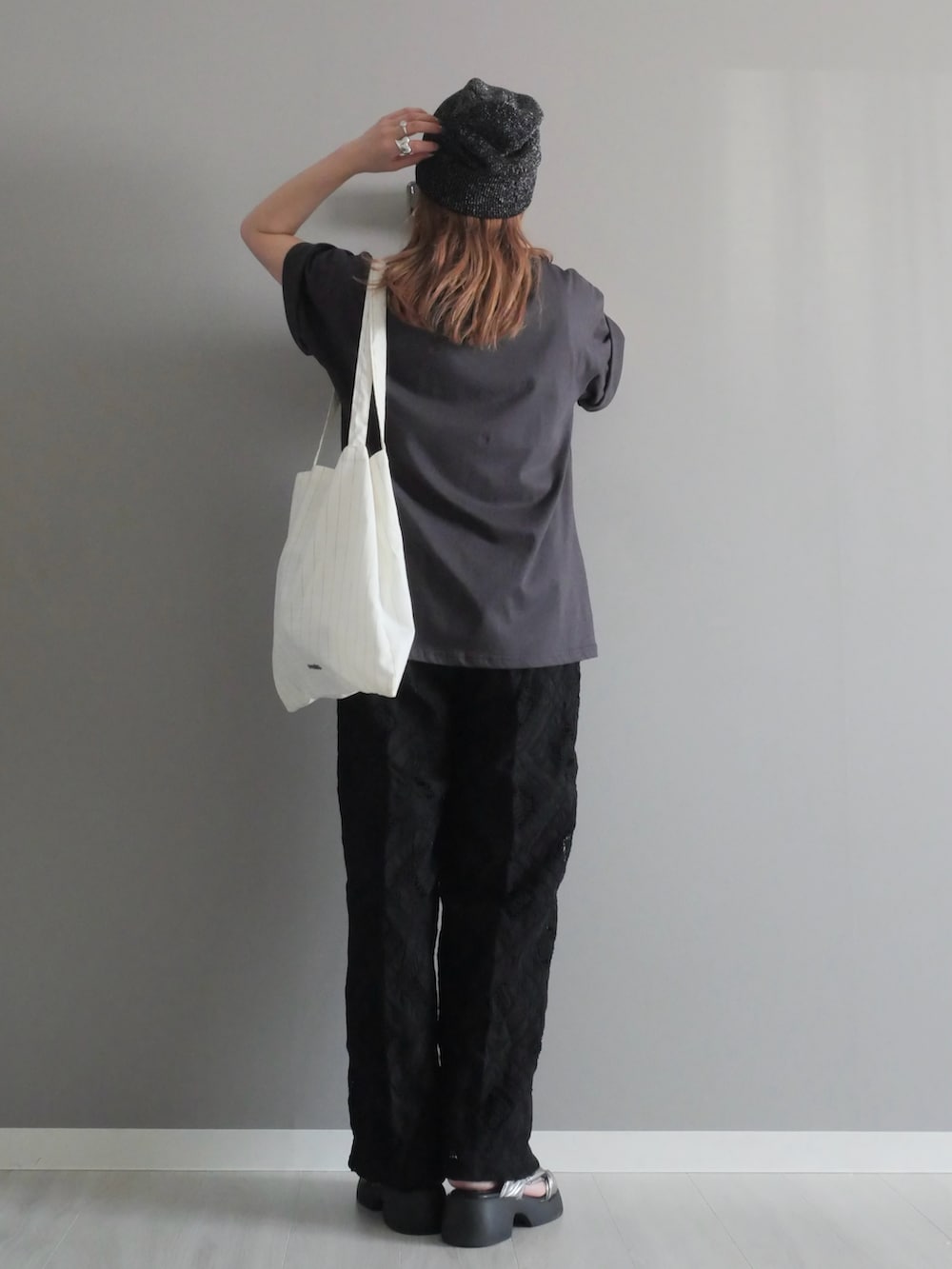 ブラック系のスラックス、グレー系のTシャツ/カットソー、ホワイト系のトートバッグを着用したレディースの夏コーディネートの4枚目の写真