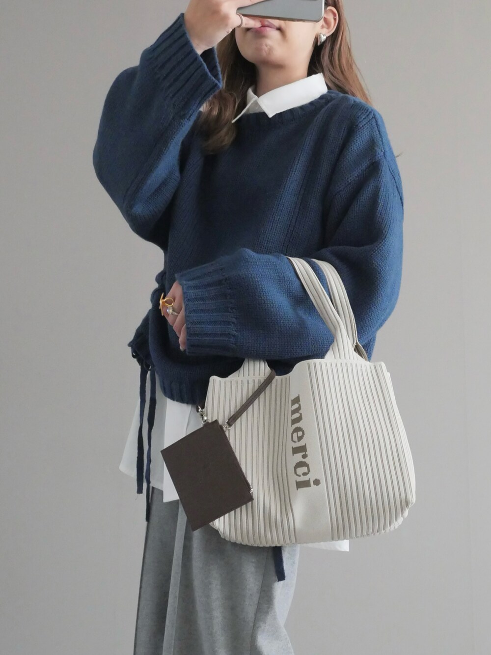 ブルー系のニット/セーター、ホワイト系のシャツ/ブラウス、グレー系のパンツを着用したレディースの冬コーディネートの2枚目の写真