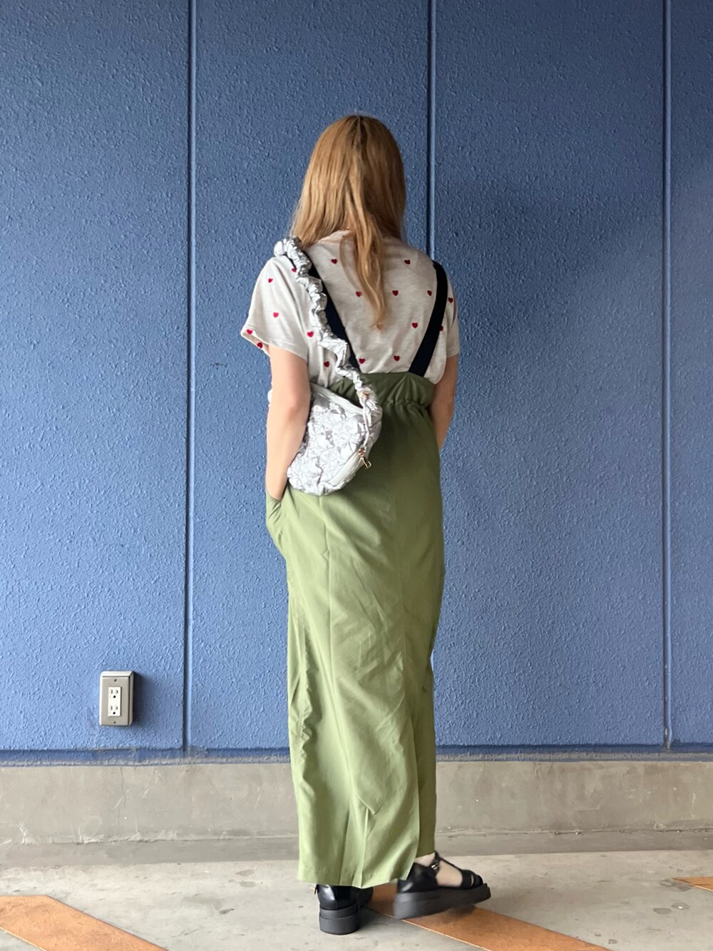 グリーン系のジャンパースカート、ベージュ系のTシャツ/カットソー、シルバー系のハンドバッグを着用したレディースの夏コーディネートの4枚目の写真