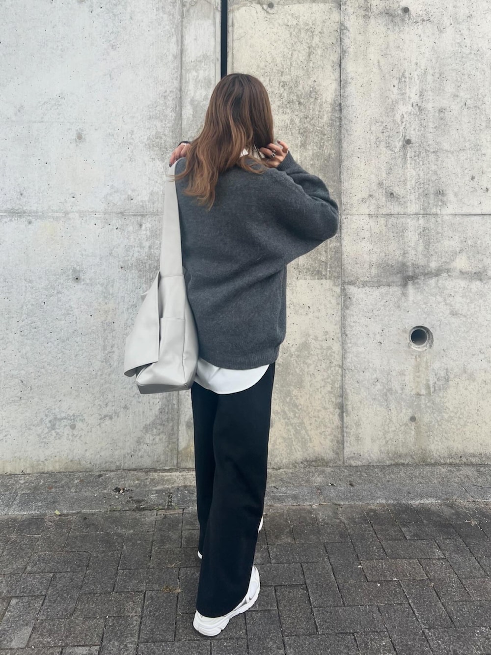 グレー系のニット/セーター、ホワイト系のシャツ/ブラウス、グレー系のパンツを着用したレディースの冬コーディネートの2枚目の写真