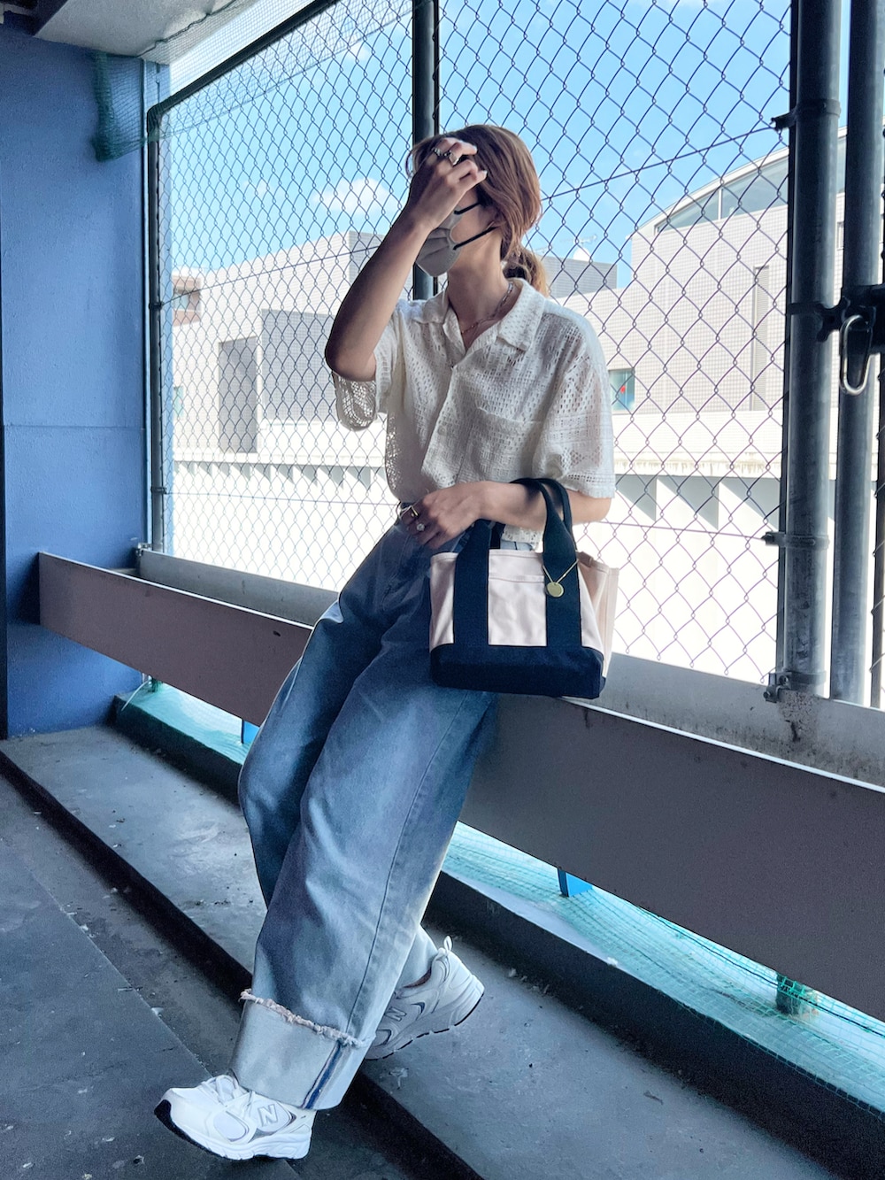 ホワイト系のトートバッグ、ホワイト系のシャツ/ブラウス、ブルー系のデニムパンツを着用したレディースの夏コーディネートの3枚目の写真