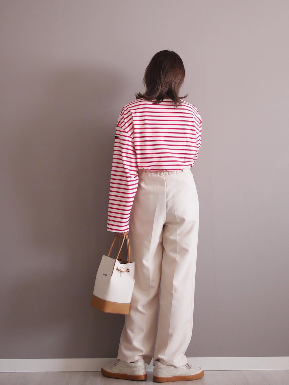 ホワイト系のTシャツ/カットソー、ホワイト系のハンドバッグ、ベージュ系のスニーカーを着用したレディースの春コーディネートの2枚目の写真