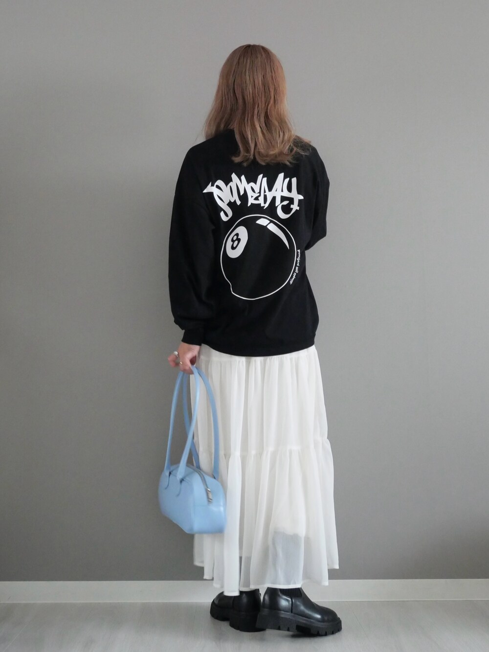 ブラック系のTシャツ/カットソー、ホワイト系のスカート、ブラック系のブーツを着用したレディースの秋コーディネートの3枚目の写真