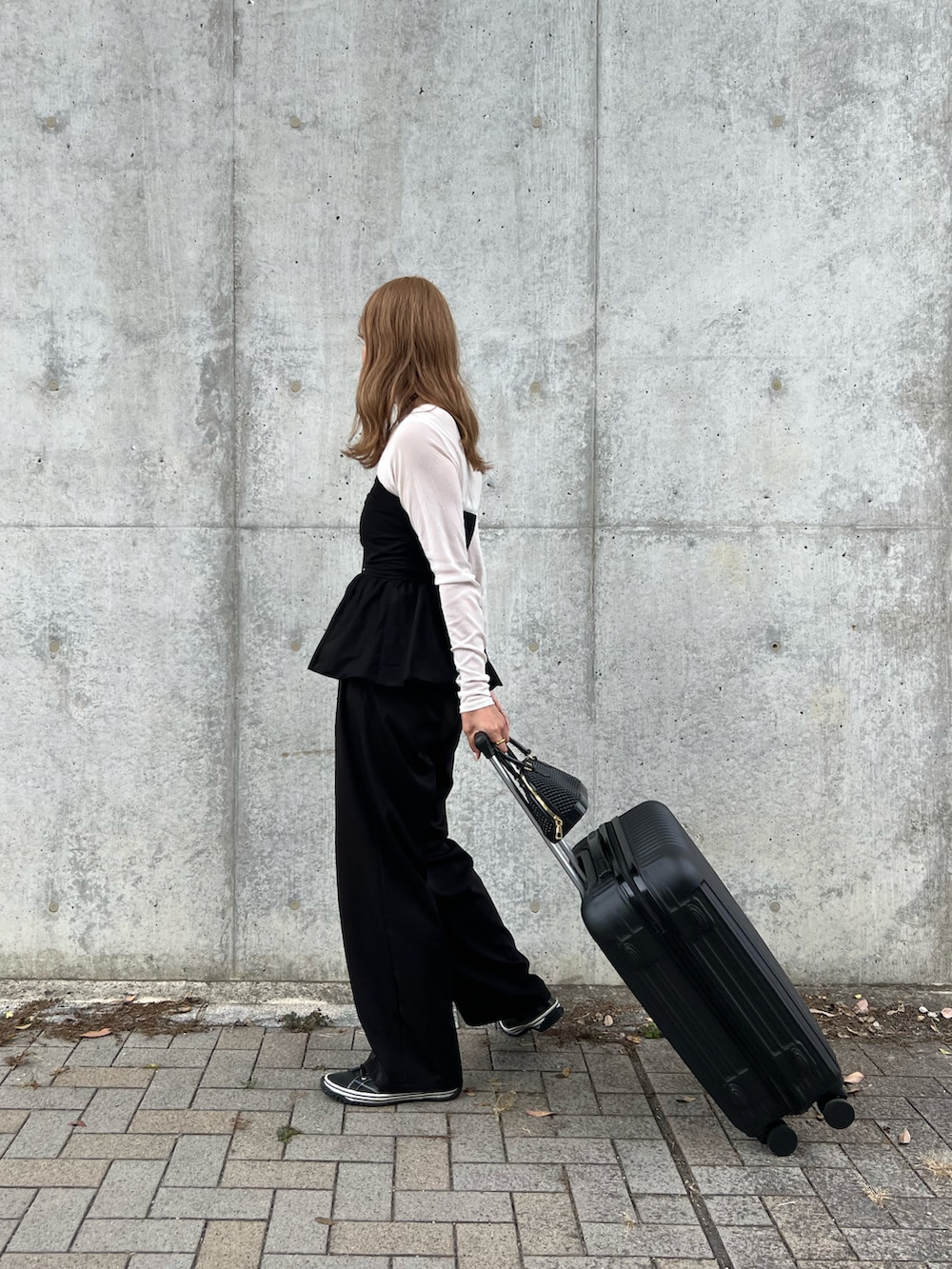 ブラック系のチューブトップ、ホワイト系のTシャツ/カットソー、ブラック系のスラックスを着用したレディースの秋コーディネートの2枚目の写真