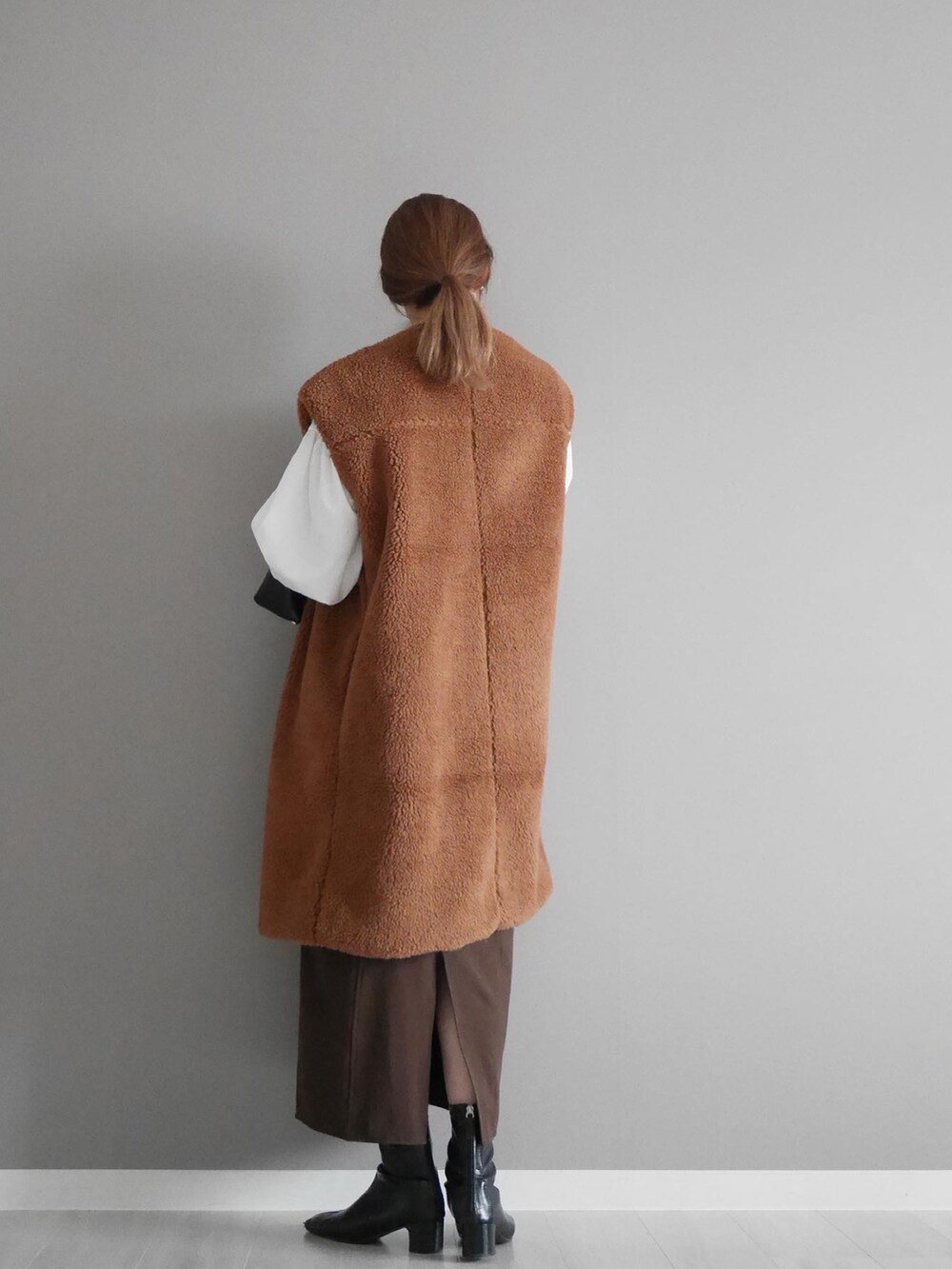 ブラウン系のベスト、ブラウン系のスカート、ブラック系のショルダーバッグを着用したレディースの秋コーディネートの4枚目の写真