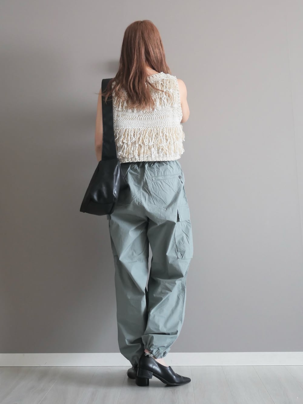 ホワイト系のベスト、グリーン系のパンツ、ブラック系のショルダーバッグを着用したレディースの春コーディネートの4枚目の写真