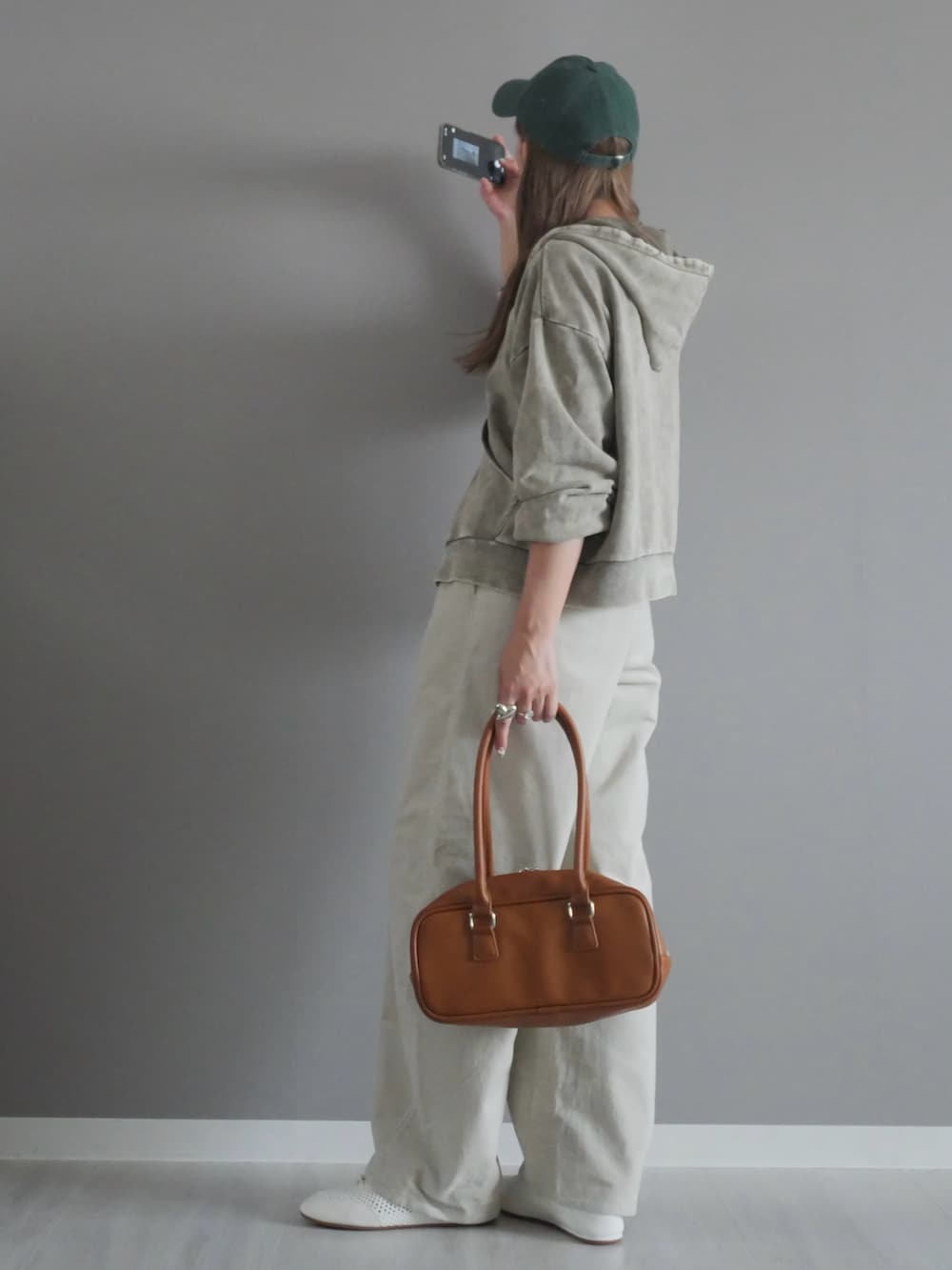 グレー系のパーカー、イエロー系のボストンバッグ、シルバー系のネックレスを着用したレディースの秋コーディネートの2枚目の写真