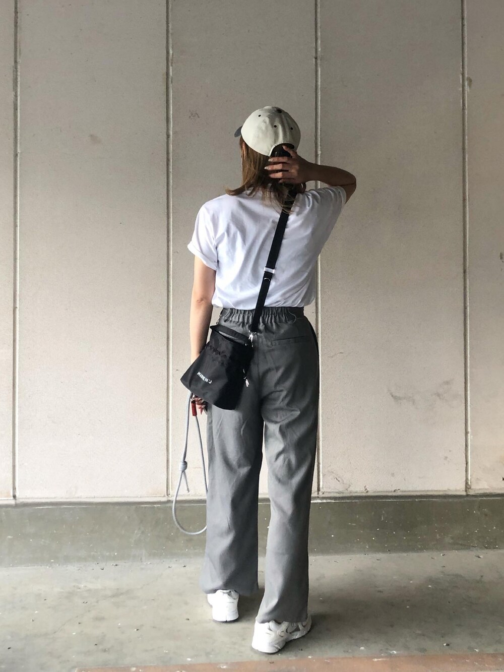グレー系のスラックス、ホワイト系のTシャツ/カットソー、ブラック系のバッグを着用したレディースの夏コーディネートの4枚目の写真