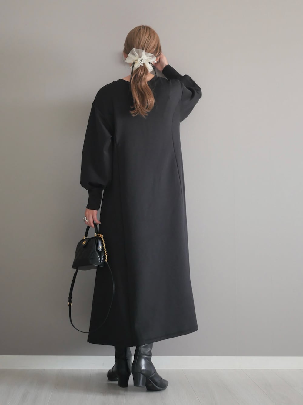 ブラック系のトートバッグ、ブラック系のワンピース、ブラック系のブーツを着用したレディースの秋コーディネートの5枚目の写真