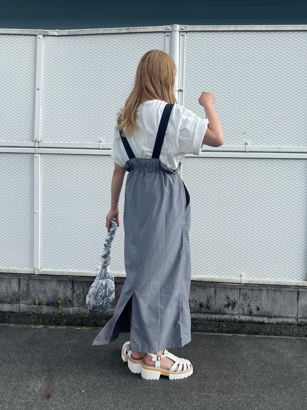 グレー系のジャンパースカート、ホワイト系のTシャツ/カットソー、シルバー系のハンドバッグを着用したレディースの夏コーディネートの2枚目の写真