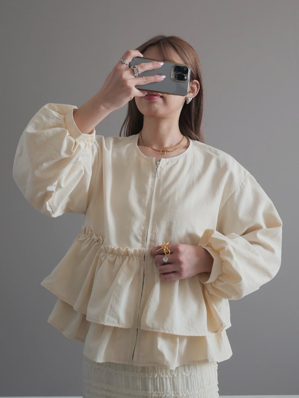 ホワイト系のノーカラージャケット、ホワイト系のスカート、ホワイト系のハンドバッグを着用したレディースの春コーディネートの2枚目の写真