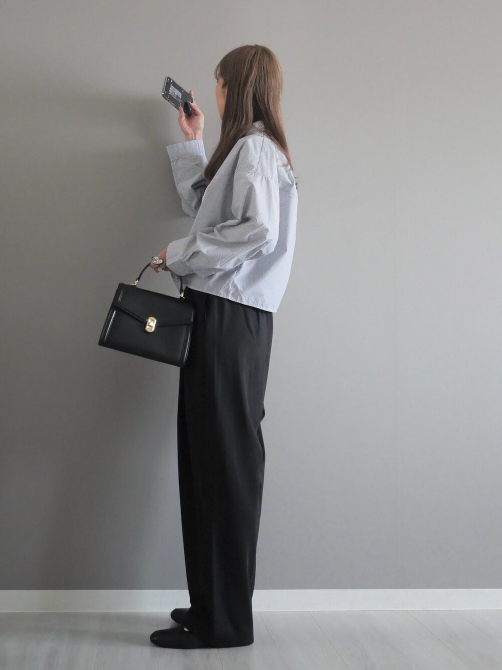 ブラック系のトートバッグ、ブラック系のスラックス、ブラック系のパンプスを着用したレディースの秋コーディネートの3枚目の写真