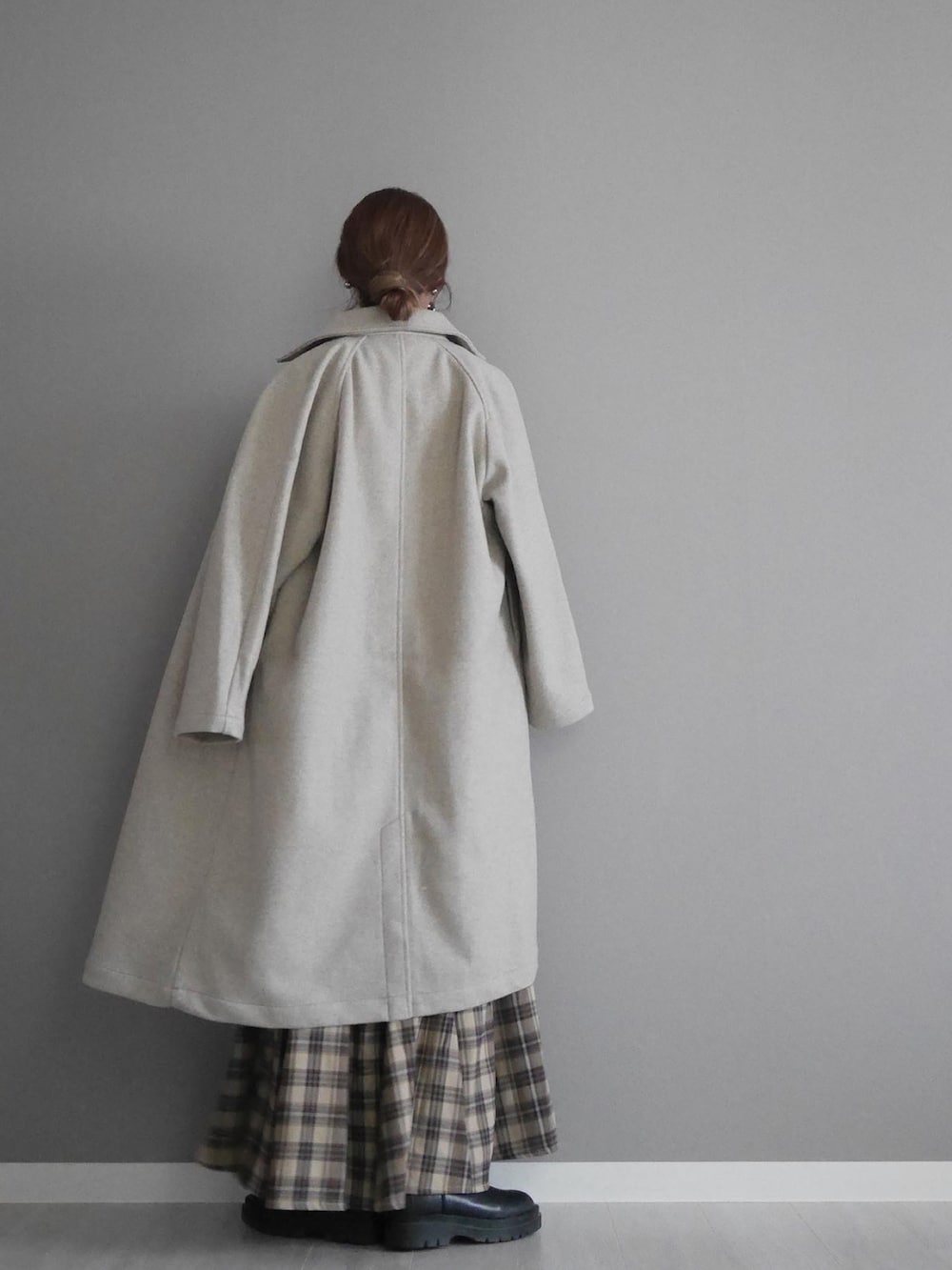 ベージュ系のステンカラーコート、レッド系のカーディガン/ボレロ、ベージュ系のスカートを着用したレディースの秋コーディネートの4枚目の写真