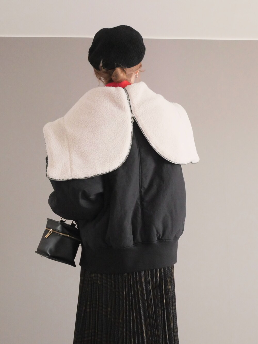 ブラック系のブルゾン、グレー系のスカート、ブラック系のショルダーバッグを着用したレディースの秋コーディネートの4枚目の写真