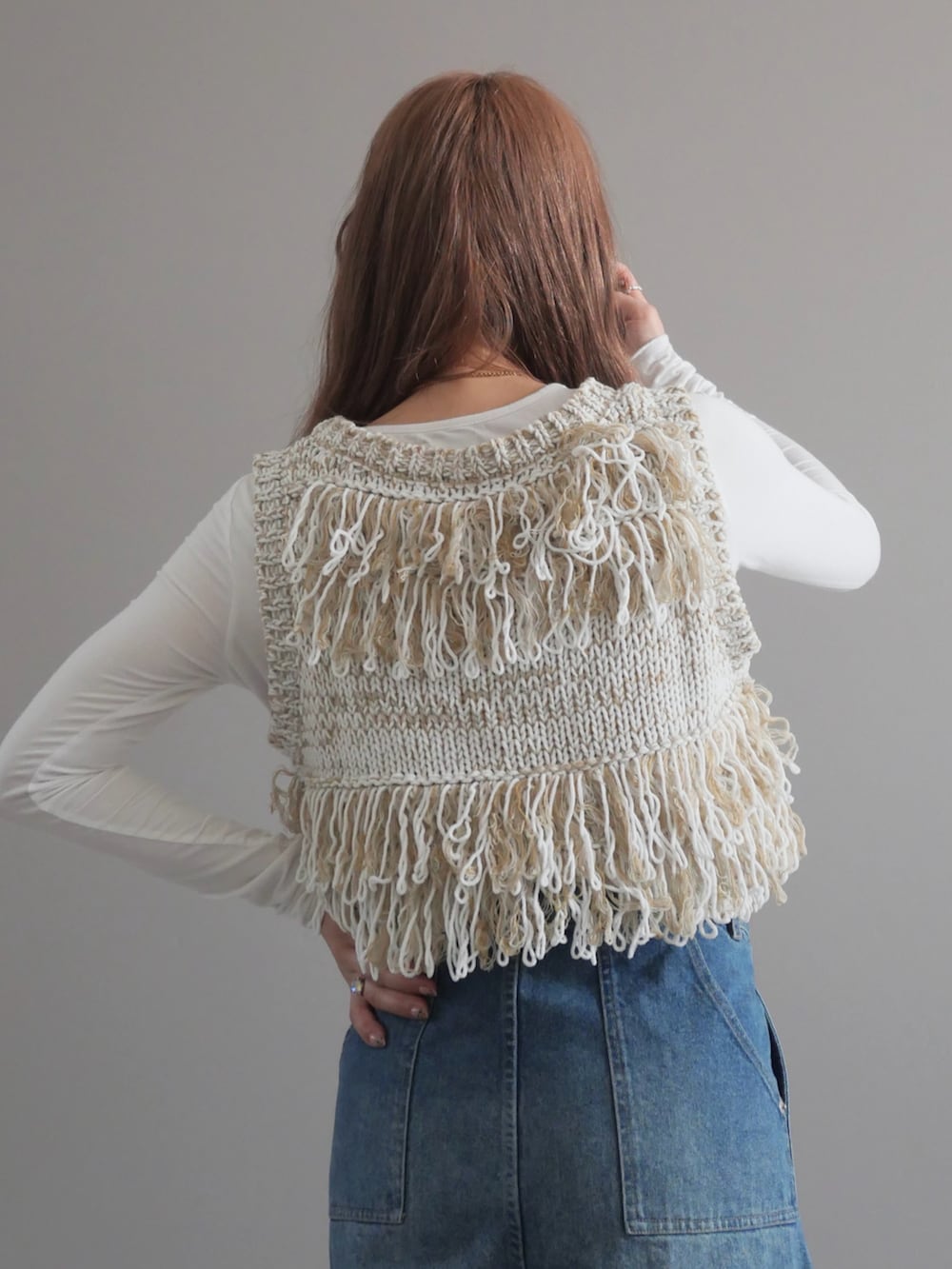 ホワイト系のベスト、ブルー系のデニムパンツ、ホワイト系のハンドバッグを着用したレディースの春コーディネートの3枚目の写真