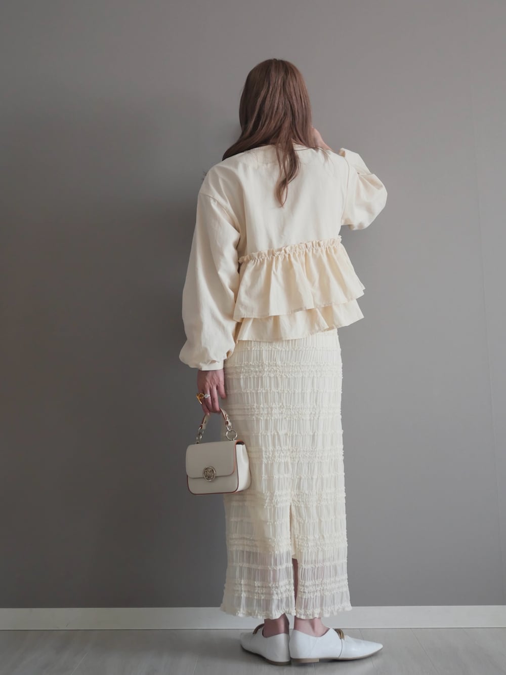 ホワイト系のノーカラージャケット、ホワイト系のスカート、ホワイト系のハンドバッグを着用したレディースの春コーディネートの4枚目の写真