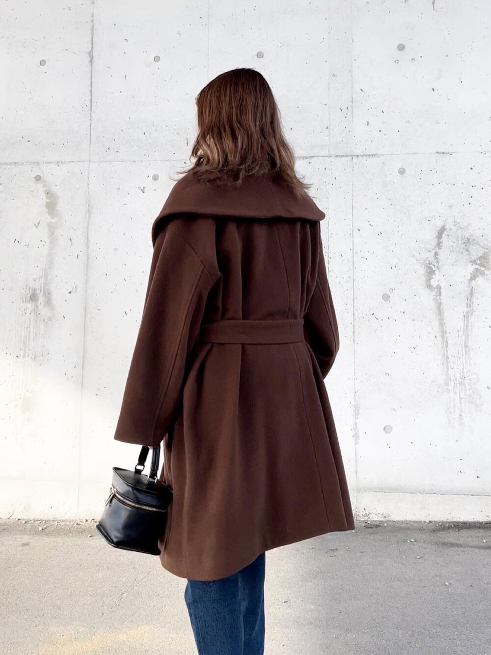 ブラウン系のその他アウター、ブラック系のニット/セーター、ブルー系のデニムパンツを着用したレディースの冬コーディネートの4枚目の写真